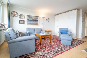 Wohnzimmer mit Sofa, Sessel und Schrankbetten