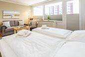Wohn-/Schlafraum mit feststehendem Doppelbett, Sofa und Sessel