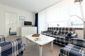 Wohnzimmer mit Couchgarnitur, Sessel, TV und Zutritt zum Schlafzimmer 